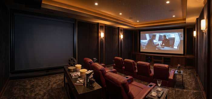 A luxurious home theater features red leather recliners and a starlight ceiling, utilizing large motorized blackout roller shades on the side wall to completely block out external light for an optimal movie-viewing experience.