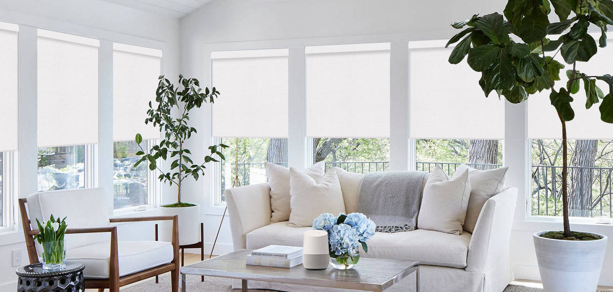 Pure white living room with white sofa, Windows with motorized roller shades surround the walls on both sides.