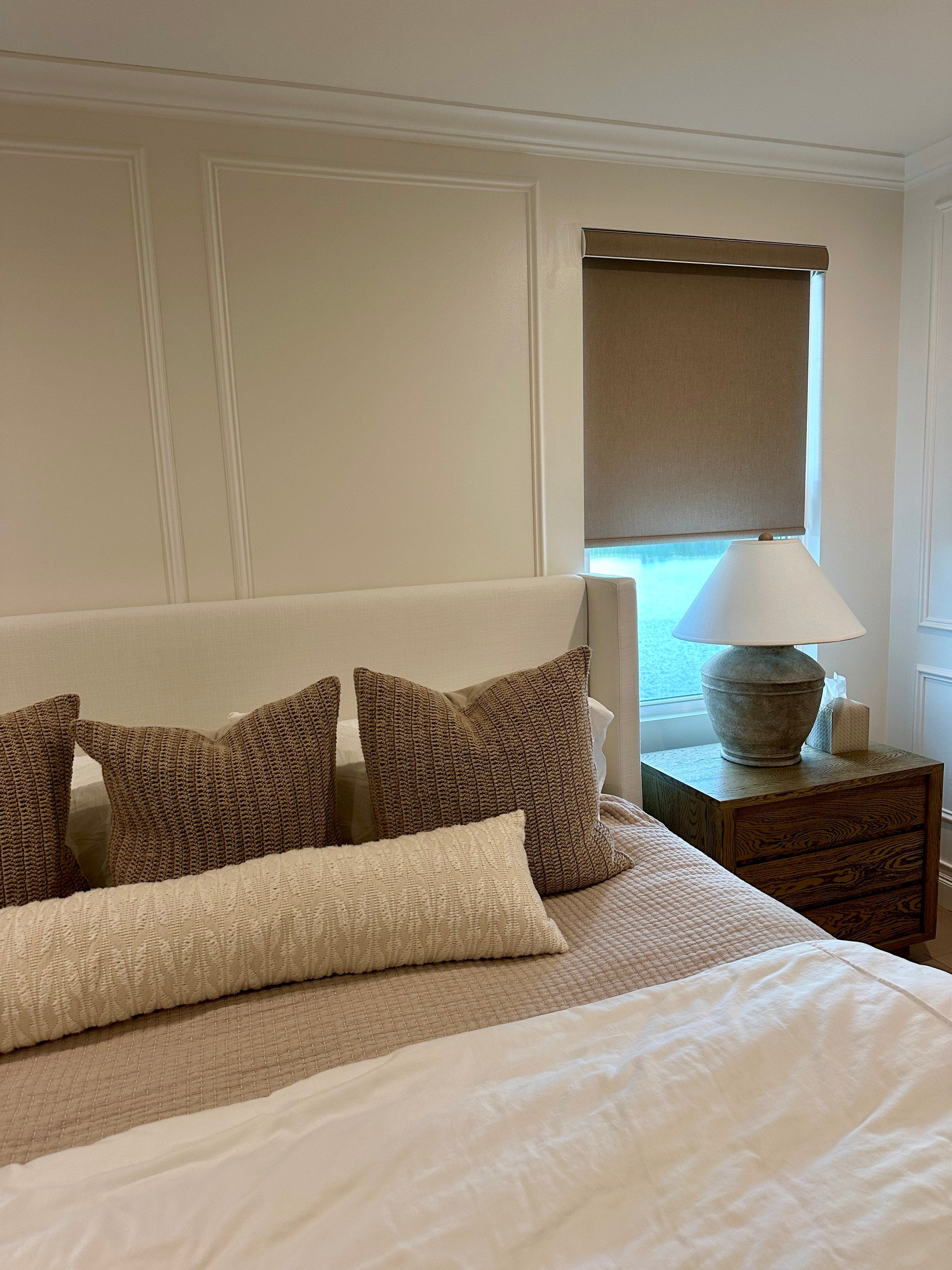 A calm bedroom with a motorized roller shade lowered for the night