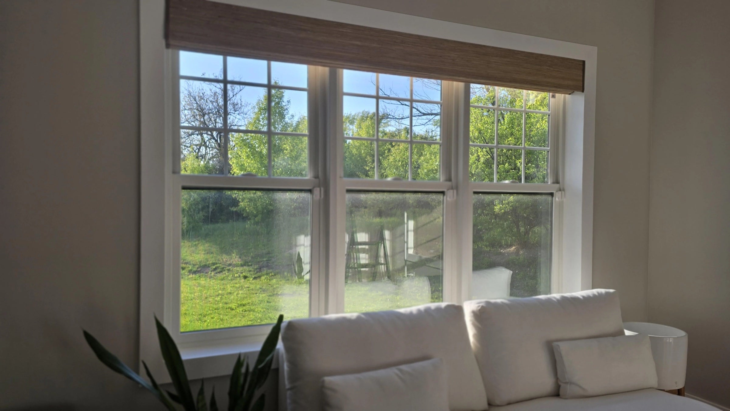 Woven wood shade open above living room windows